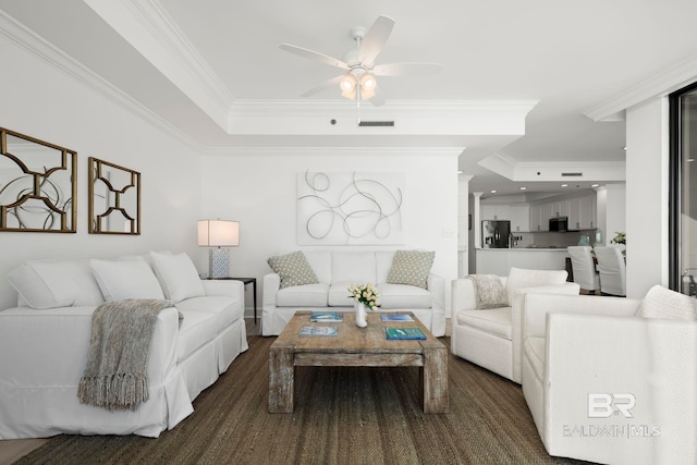 living room with dark hardwood / wood-style flooring, a raised ceiling, ceiling fan, and crown molding