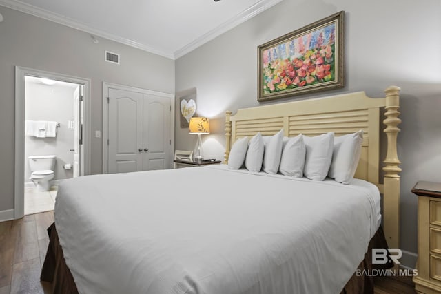 bedroom with dark wood finished floors, visible vents, a closet, ensuite bath, and crown molding