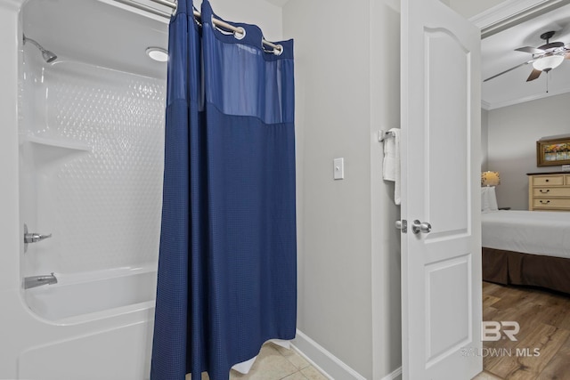 ensuite bathroom with baseboards, ceiling fan, wood finished floors, ensuite bathroom, and shower / bathtub combination with curtain