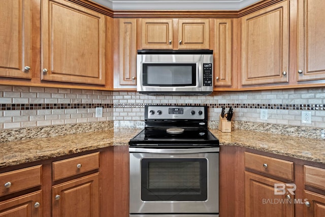 kitchen featuring stainless steel appliances, brown cabinetry, and light stone countertops