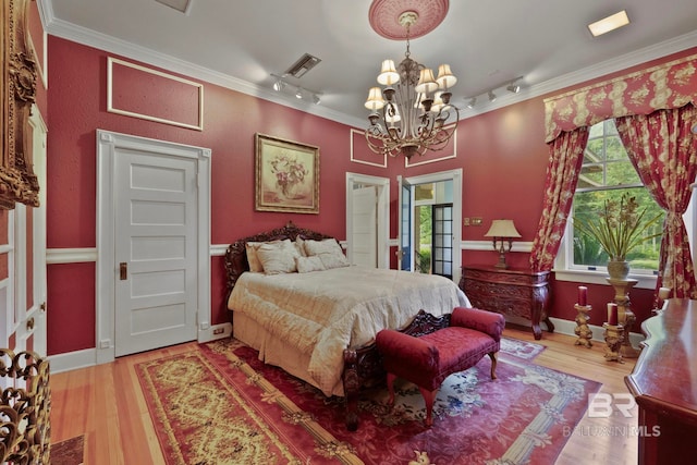 bedroom with multiple windows, a chandelier, track lighting, and light hardwood / wood-style floors