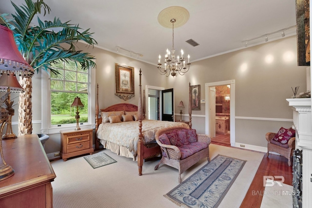 bedroom featuring crown molding, track lighting, tile patterned floors, an inviting chandelier, and ensuite bathroom