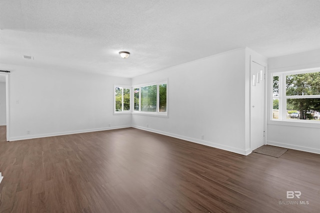 spare room with baseboards, dark wood-style floors, a textured ceiling, and visible vents