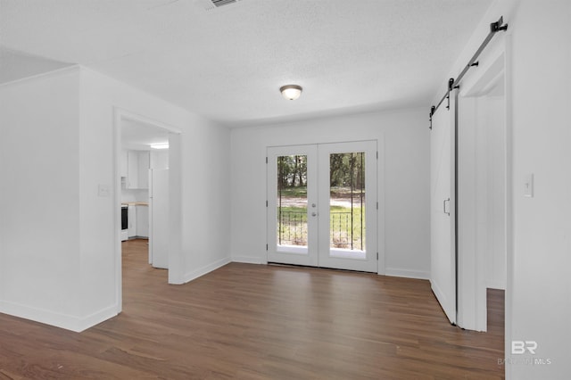 interior space featuring french doors, a barn door, baseboards, and dark wood-style floors