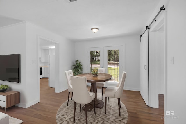 dining area with baseboards, a barn door, and wood finished floors