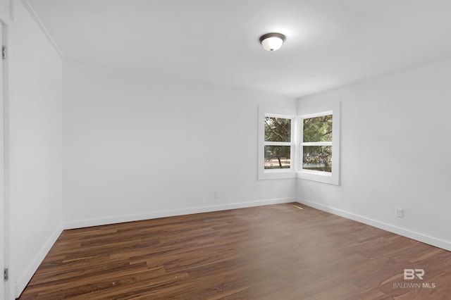 spare room with baseboards and wood finished floors