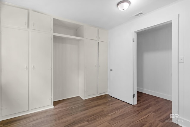 unfurnished bedroom featuring baseboards, a closet, wood finished floors, and visible vents