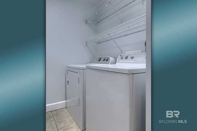 clothes washing area with independent washer and dryer and light tile patterned floors