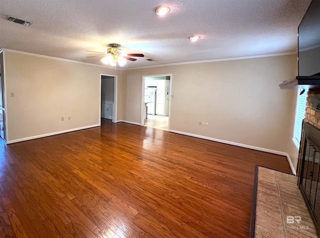 unfurnished living room with crown molding, ceiling fan, dark hardwood / wood-style flooring, a brick fireplace, and a textured ceiling