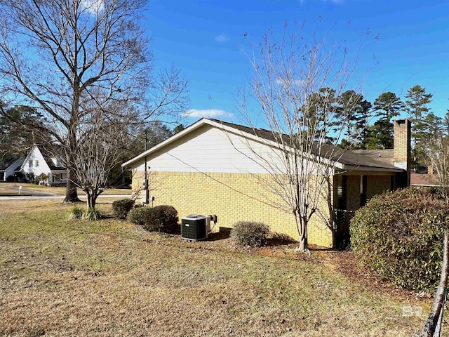 view of side of home featuring cooling unit and a lawn