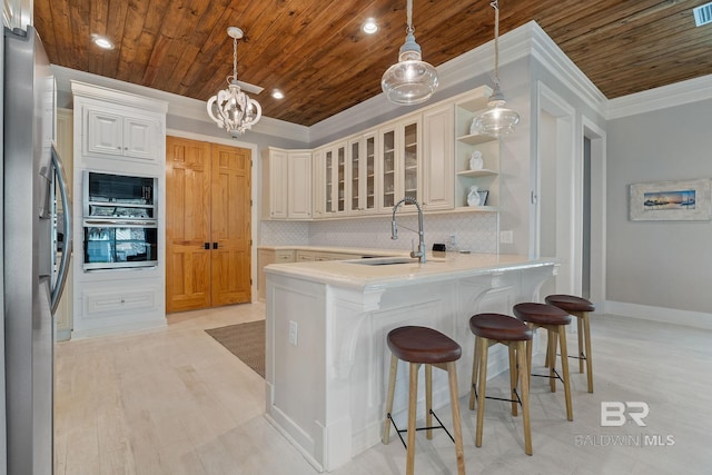 kitchen with a peninsula, ornamental molding, a sink, wood ceiling, and freestanding refrigerator