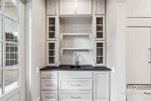 bar with white cabinets, sink, and backsplash