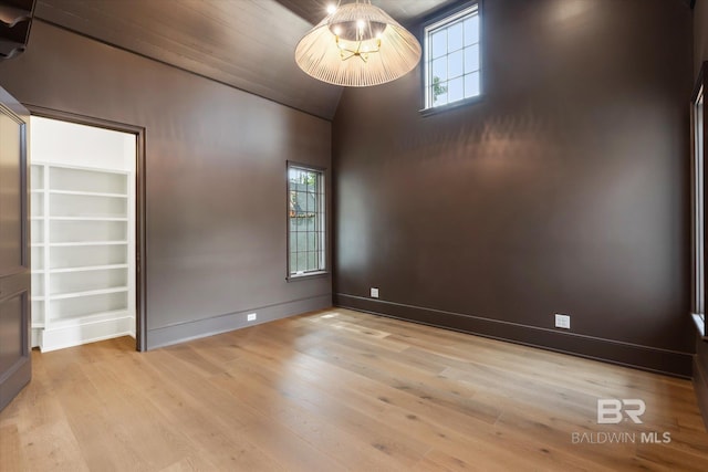 empty room featuring a healthy amount of sunlight, vaulted ceiling, and light wood-type flooring