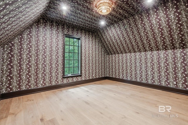 additional living space with hardwood / wood-style flooring and vaulted ceiling