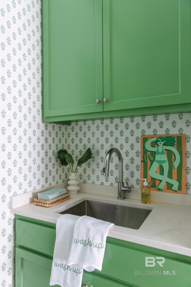 kitchen featuring sink, green cabinets, and light stone counters