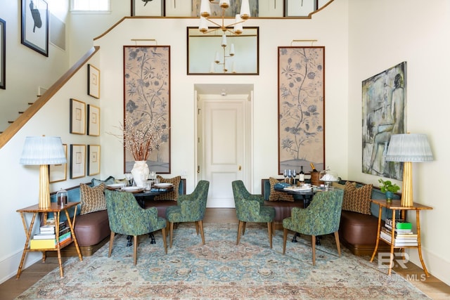 dining area featuring a notable chandelier, wood-type flooring, and a high ceiling