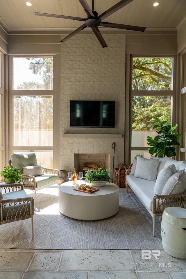 sunroom featuring wood ceiling, ceiling fan, a fireplace, and a wealth of natural light