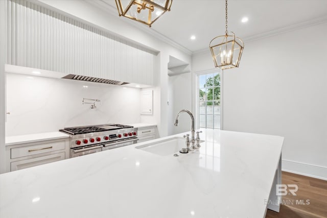 kitchen featuring sink, double oven range, hanging light fixtures, light stone counters, and an island with sink