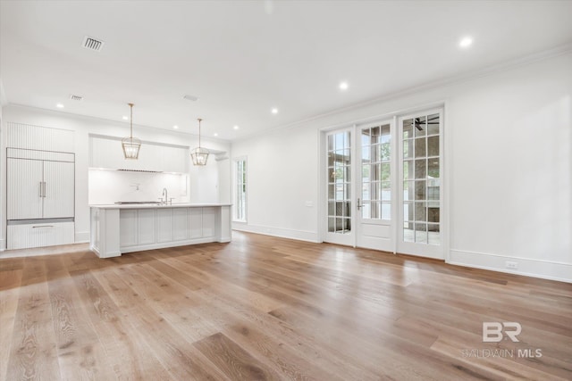 unfurnished living room featuring sink, light hardwood / wood-style flooring, and ornamental molding