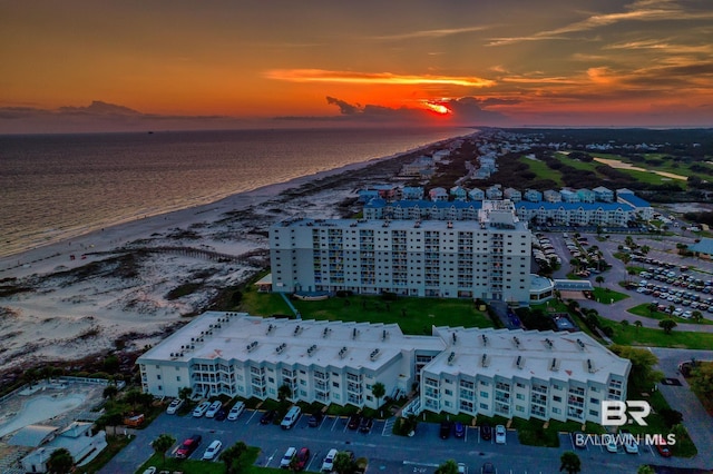 aerial view at dusk with a water view and a view of the beach