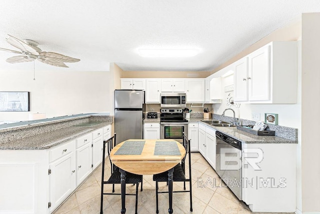 kitchen featuring a ceiling fan, light stone countertops, white cabinetry, a sink, and stainless steel appliances