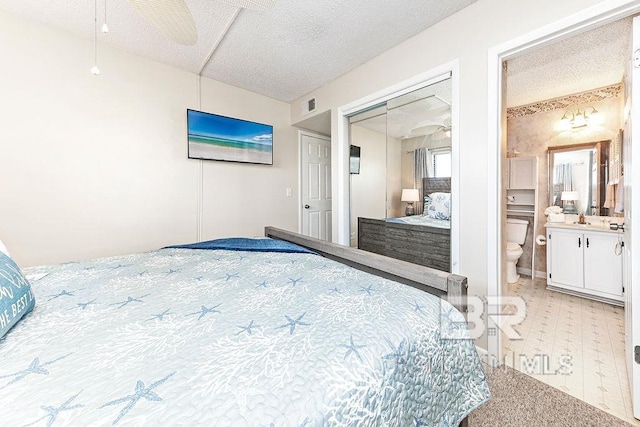 bedroom with a sink, a textured ceiling, connected bathroom, and visible vents