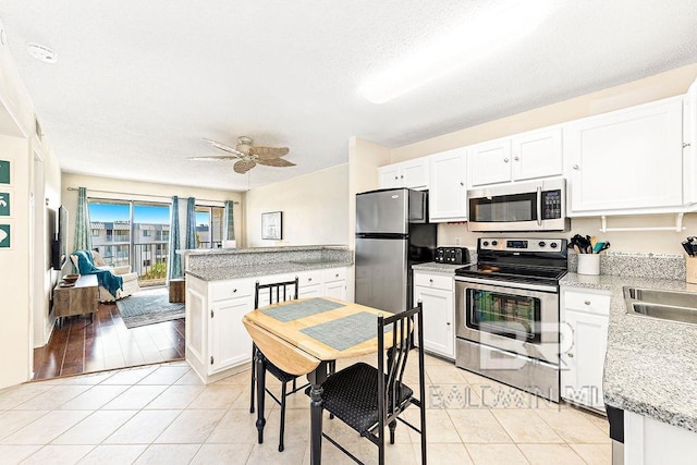 kitchen featuring light tile patterned floors, ceiling fan, stainless steel appliances, and white cabinets