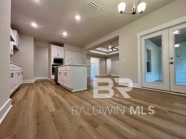 kitchen with white cabinetry, pendant lighting, light hardwood / wood-style floors, stainless steel microwave, and a center island