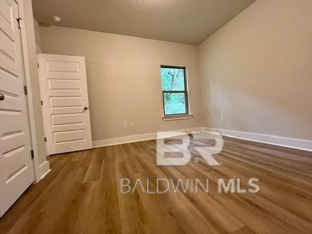 empty room with dark hardwood / wood-style floors and a textured ceiling