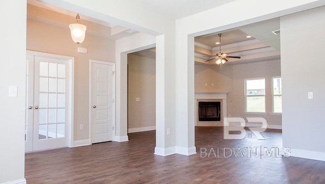 unfurnished living room with dark hardwood / wood-style flooring, crown molding, ceiling fan, and a raised ceiling