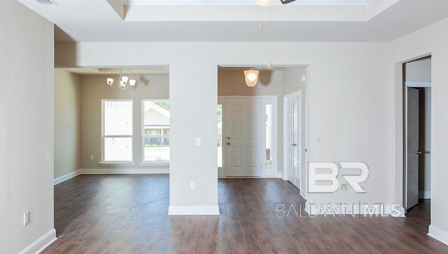 empty room featuring dark wood-type flooring and a notable chandelier