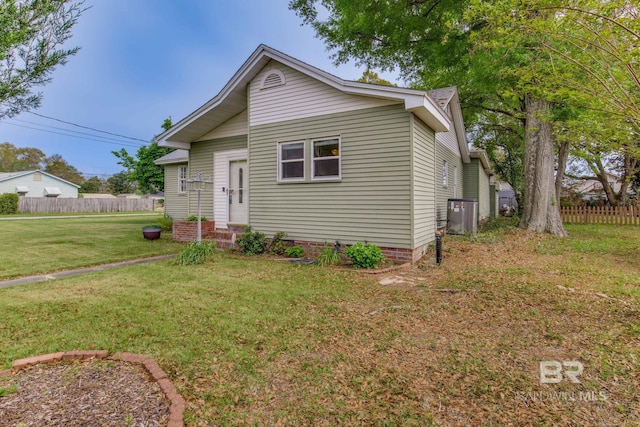 bungalow-style house with cooling unit, fence, and a front lawn