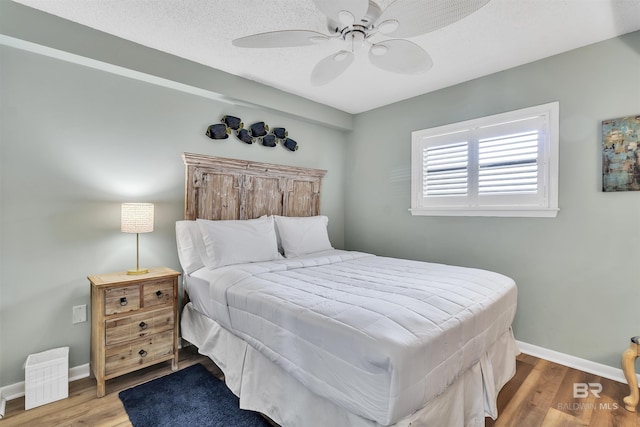 bedroom featuring a textured ceiling, wood finished floors, baseboards, and ceiling fan