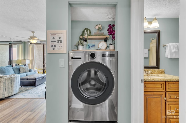 laundry room featuring a sink, light wood-style floors, a textured ceiling, and washer / dryer