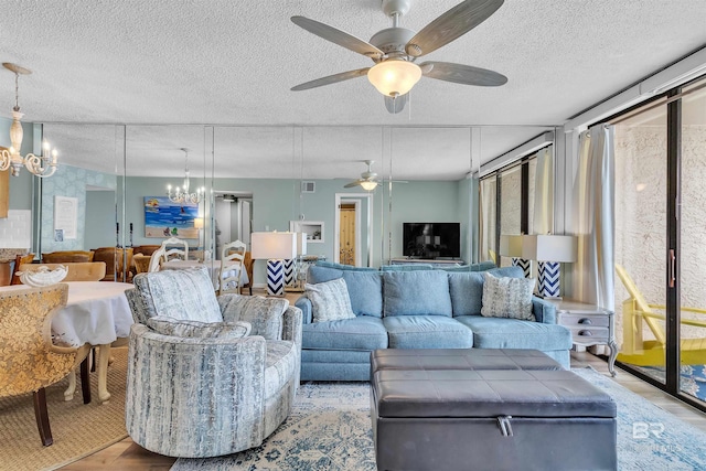 living area with ceiling fan with notable chandelier, a textured ceiling, and wood finished floors