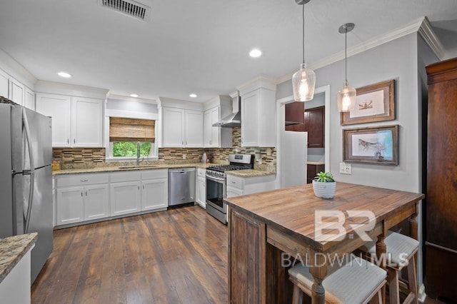 kitchen featuring a sink, stainless steel appliances, white cabinets, visible vents, and wall chimney range hood