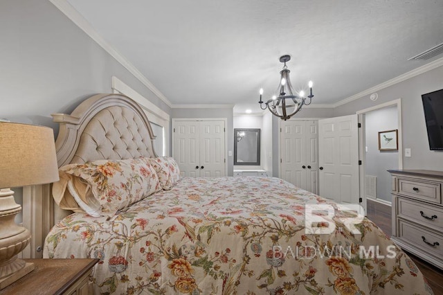 bedroom with an inviting chandelier, wood finished floors, multiple closets, crown molding, and visible vents