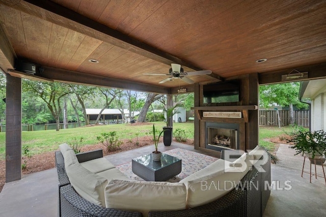 view of patio featuring ceiling fan, fence, and an outdoor living space with a fireplace