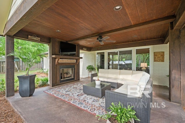 view of patio / terrace with an outdoor living space with a fireplace, fence, and a ceiling fan