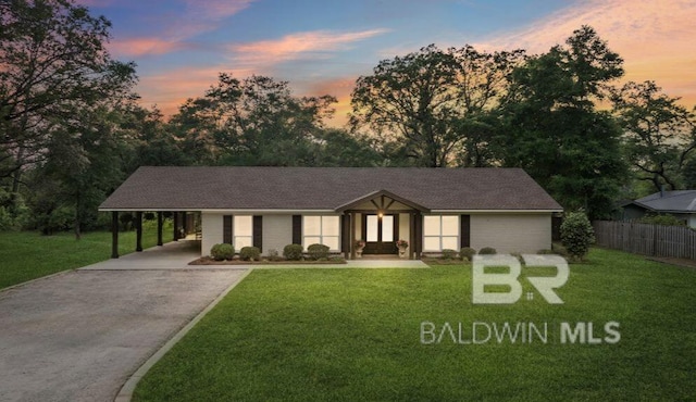 view of front of property featuring a yard, an attached carport, aphalt driveway, and fence