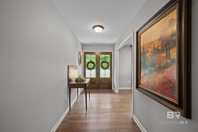 doorway with baseboards, dark wood finished floors, french doors, and a textured ceiling