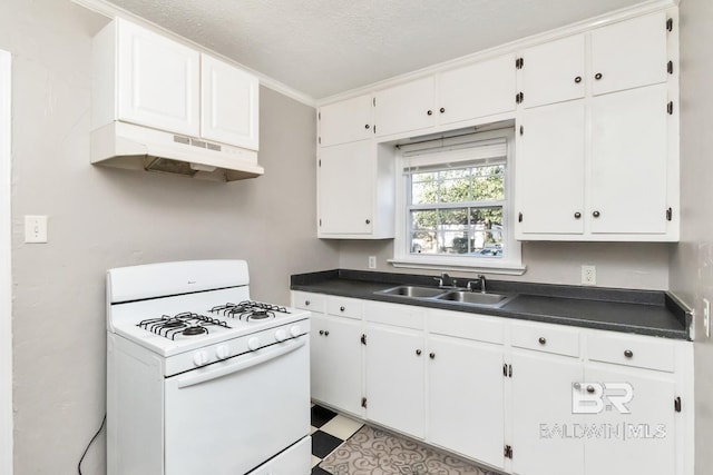 kitchen featuring white gas stove, dark countertops, a sink, and under cabinet range hood