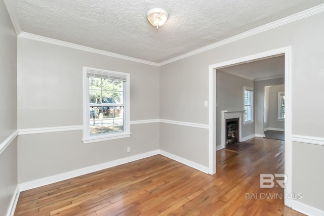 empty room featuring a wealth of natural light, a fireplace with flush hearth, hardwood / wood-style flooring, and baseboards