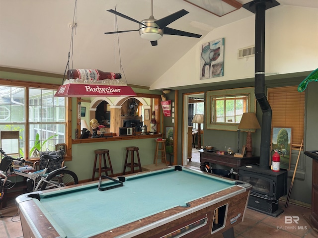 game room with tile patterned floors, vaulted ceiling, a wood stove, and pool table