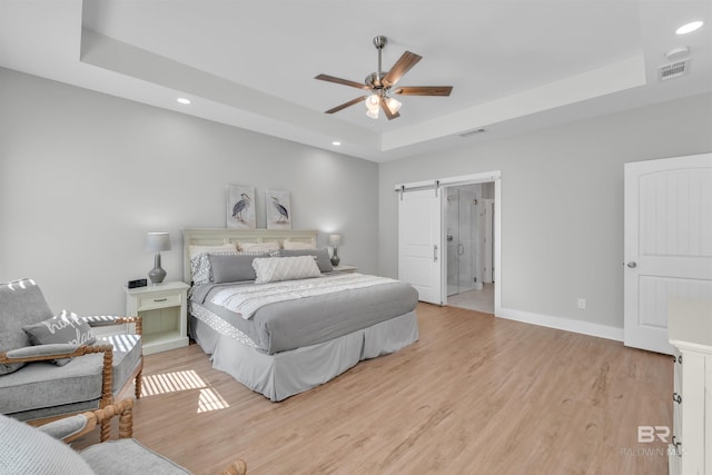 5774 Ono Ave, Pensacola, FL 32507 - bedroom featuring a raised ceiling, light wood-style flooring, recessed lighting, a barn door, and baseboards