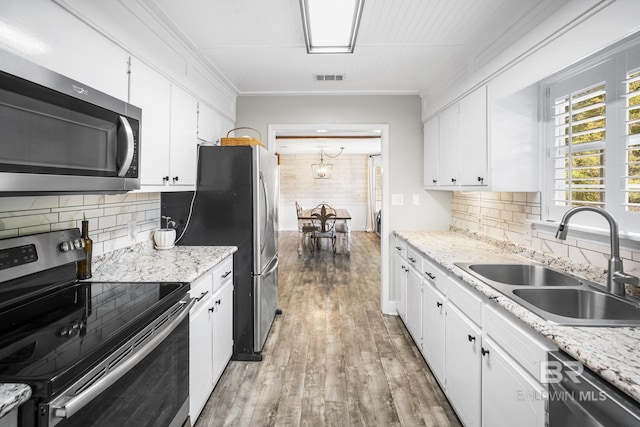 117 Richmond Rd, Daphne, AL 36526 - kitchen with appliances with stainless steel finishes, a sink, wood finished floors, white cabinets, and tasteful backsplash