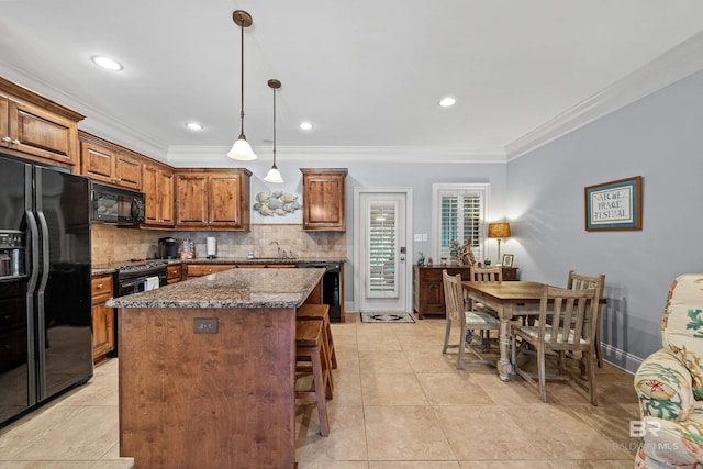 kitchen featuring a center island, backsplash, dark stone counters, black appliances, and ornamental molding