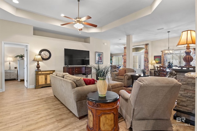 living room with a tray ceiling, light hardwood / wood-style floors, and ceiling fan