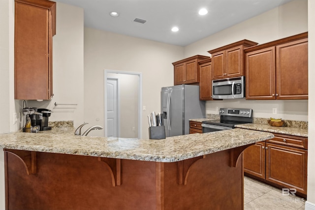 kitchen featuring appliances with stainless steel finishes, a kitchen bar, and kitchen peninsula