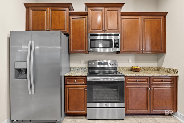 kitchen with stainless steel appliances, light stone countertops, and light tile patterned floors